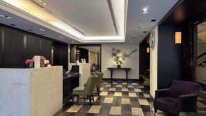 A lobby with a checkered floor, a reception desk, a seating area, and a wall-mounted sculpture. - 53 Hotel (Taichung)