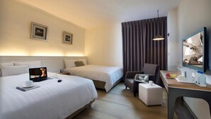 A hotel room with two beds, a desk with a laptop, a chair, a TV, and a curtain. - 53 Hotel (Taichung)
