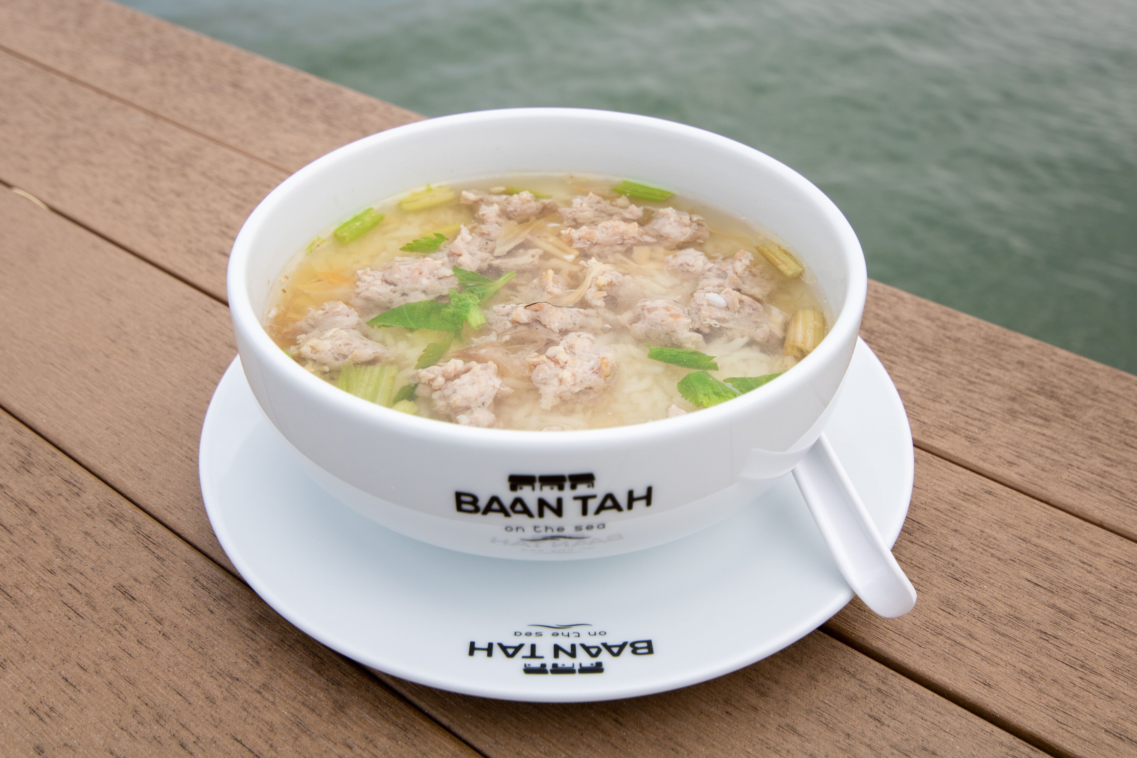 Un tazón de sopa sobre una mesa de madera con un logotipo que dice "BAANTAH on the sea".