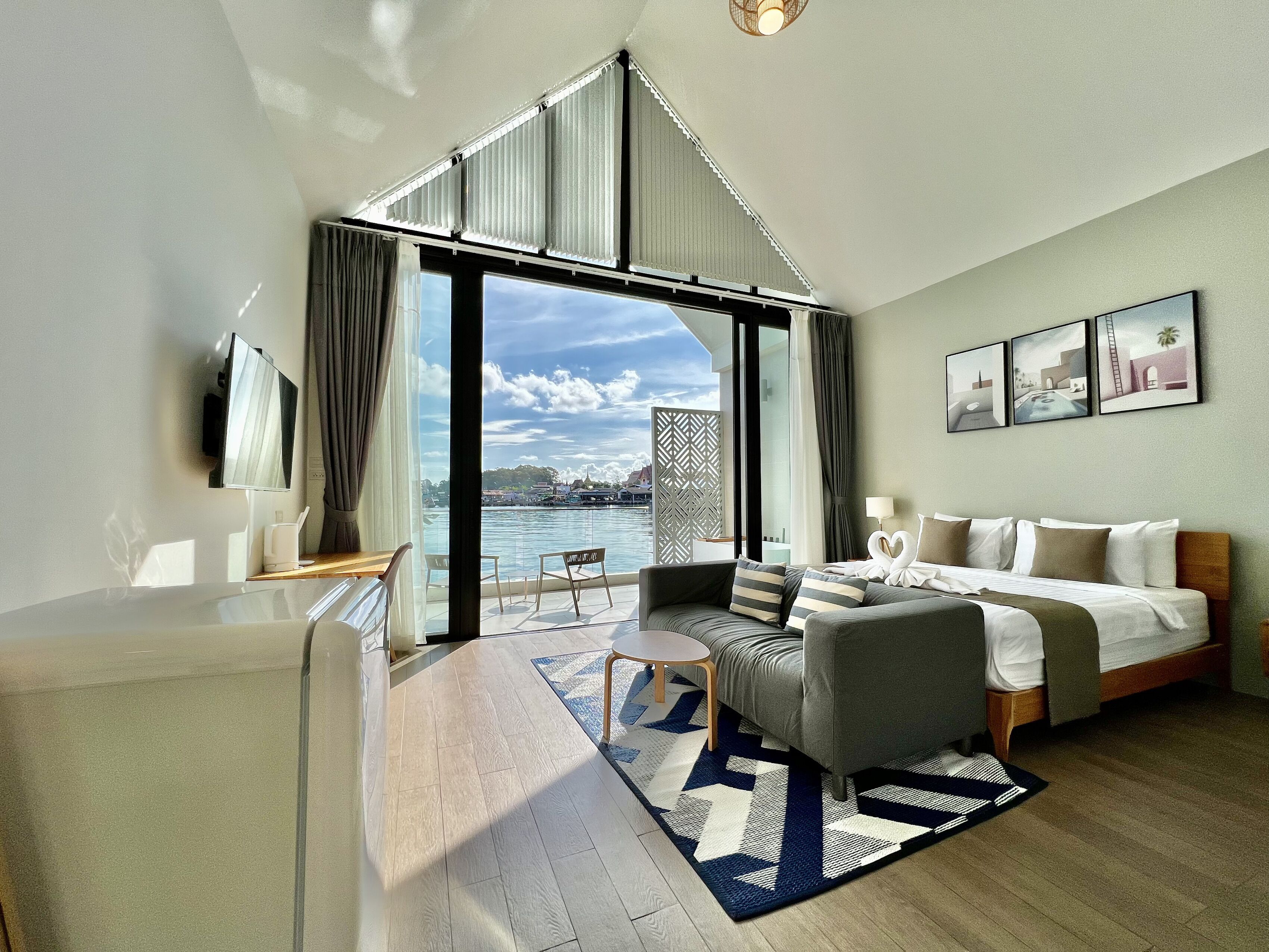 A modern hotel room with a large window offering a view of the water and cityscape.