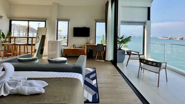 Una habitación de hotel moderna con balcón, cama, escritorio y televisor.