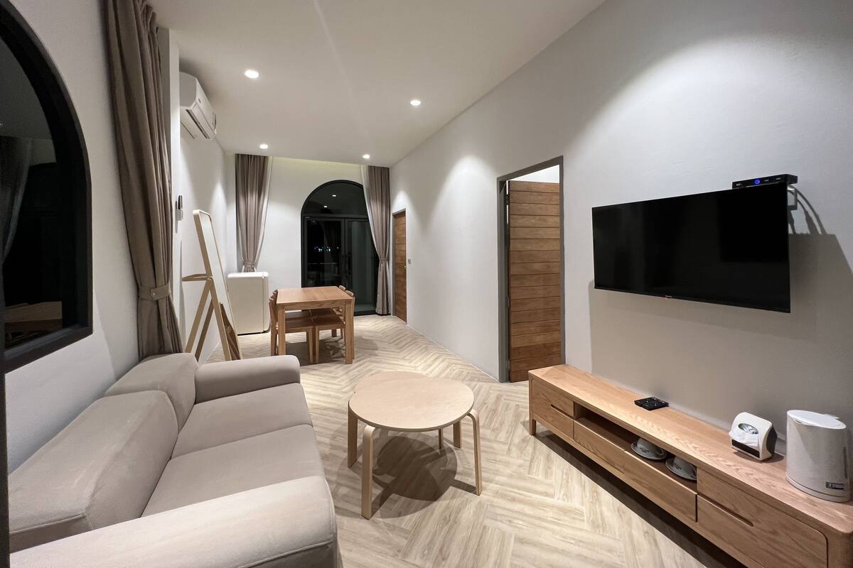 Een moderne woonkamer met een bank, een eettafel, een televisie en een koffieapparaat.