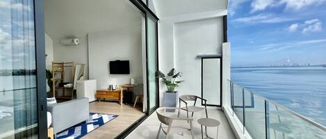 Een moderne woonkamer met een groot raam, een flatscreen televisie, een bureau en een potplant.