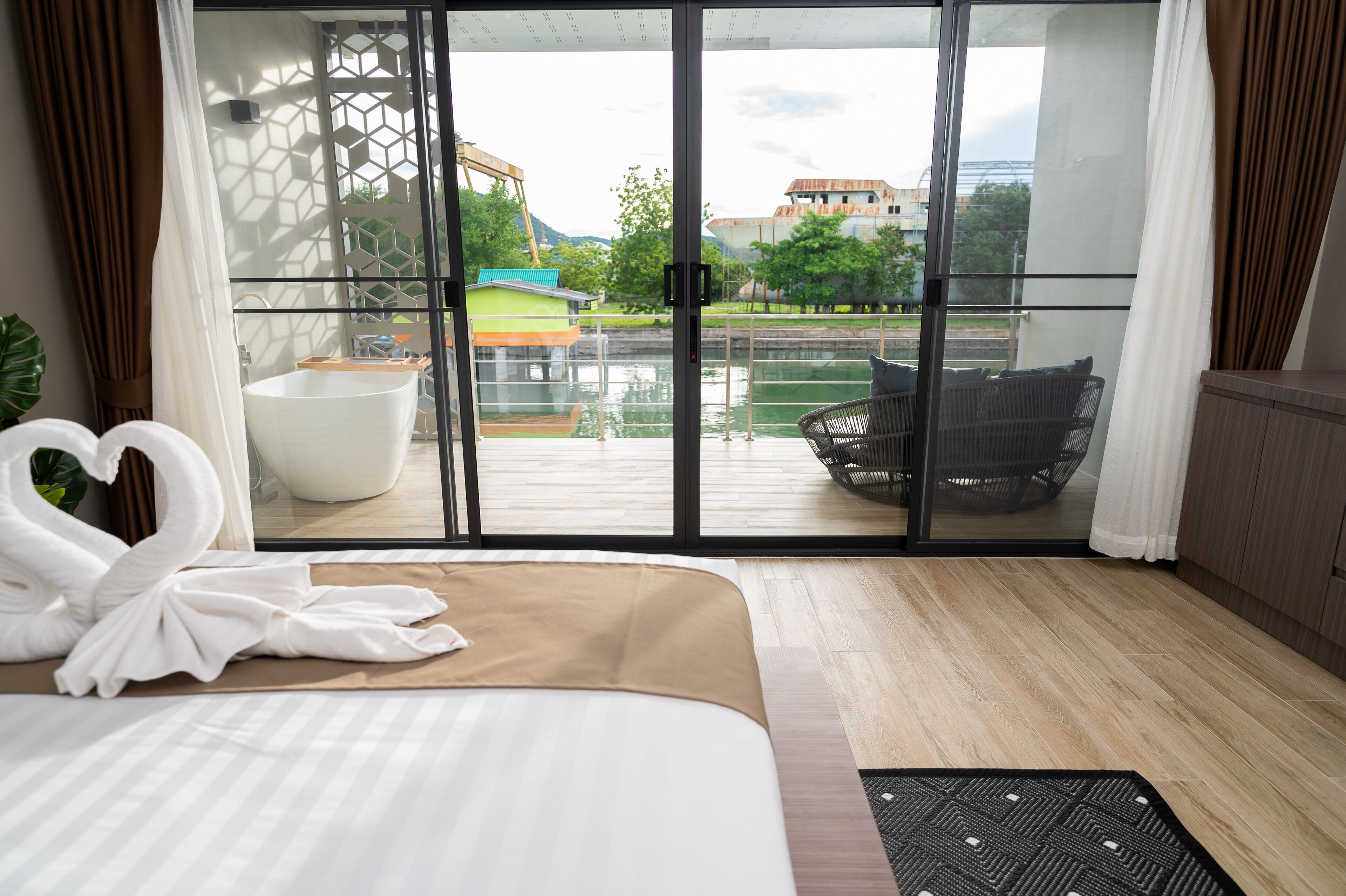 A hotel room with a large bed, a view of a pool and buildings, and a sliding glass door.