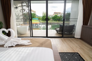 Et hotelværelse med en stor seng, udsigt til en pool og bygninger, samt en skydedør.