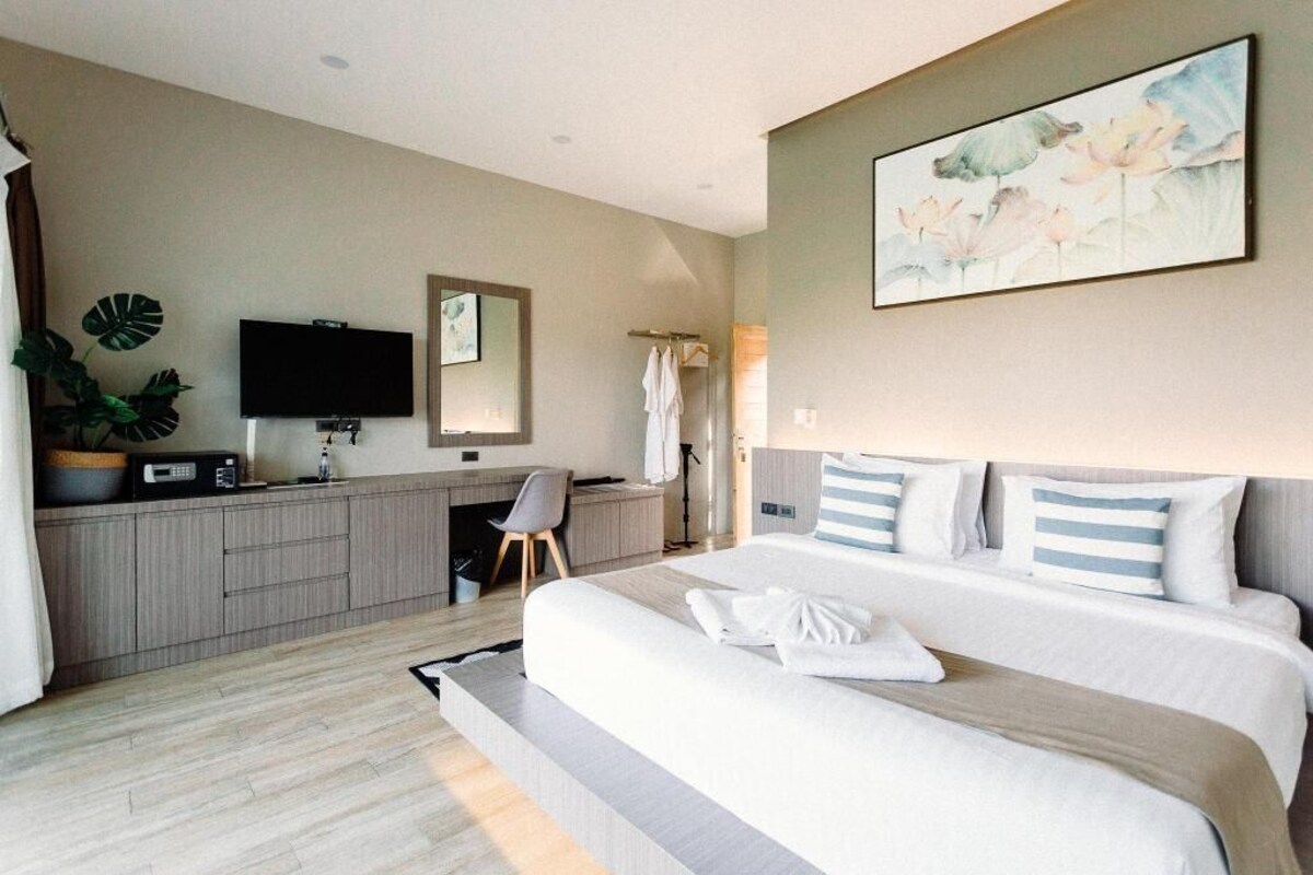 Une chambre d’hôtel avec un lit, un bureau, une télévision et un tableau.