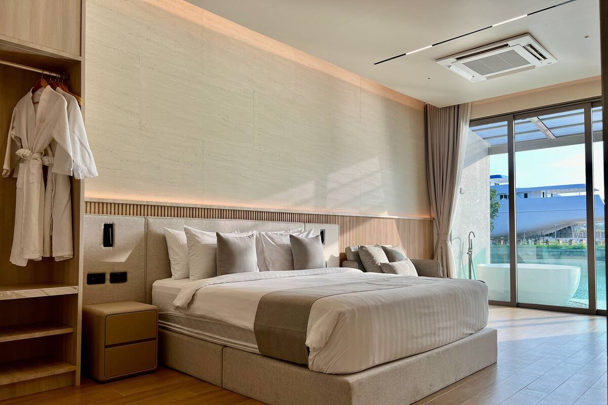 Een moderne hotelkamer met een groot bed, een inloopkast en uitzicht op het water.