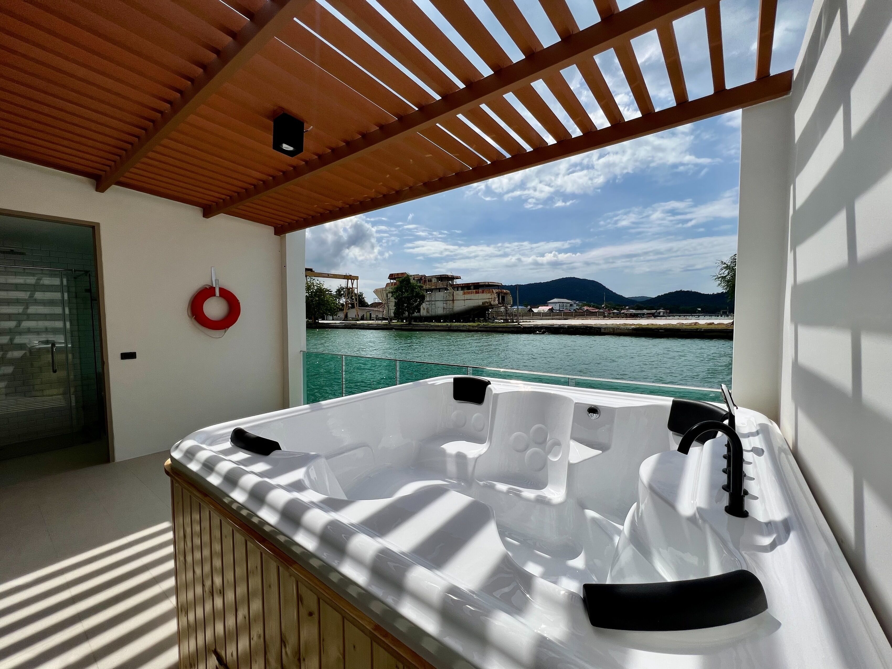 A hot tub on a balcony with a view of a body of water and buildings in the background.