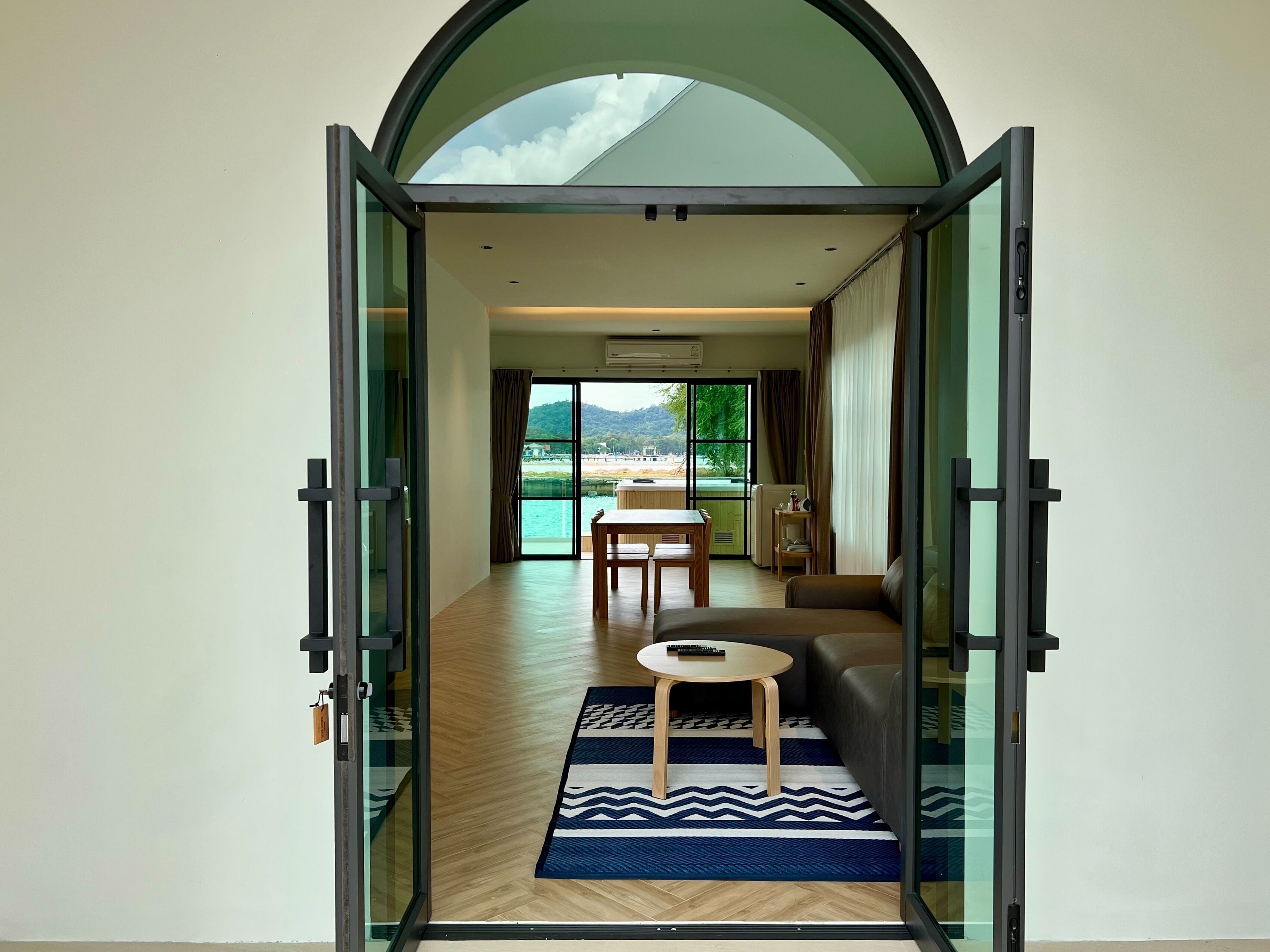 Un interior moderno con una puerta de cristal que da a un comedor y vistas a una playa.