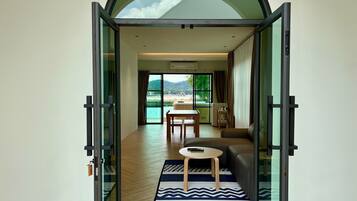Un interior moderno con una puerta de cristal que da a un comedor y vistas a una playa.