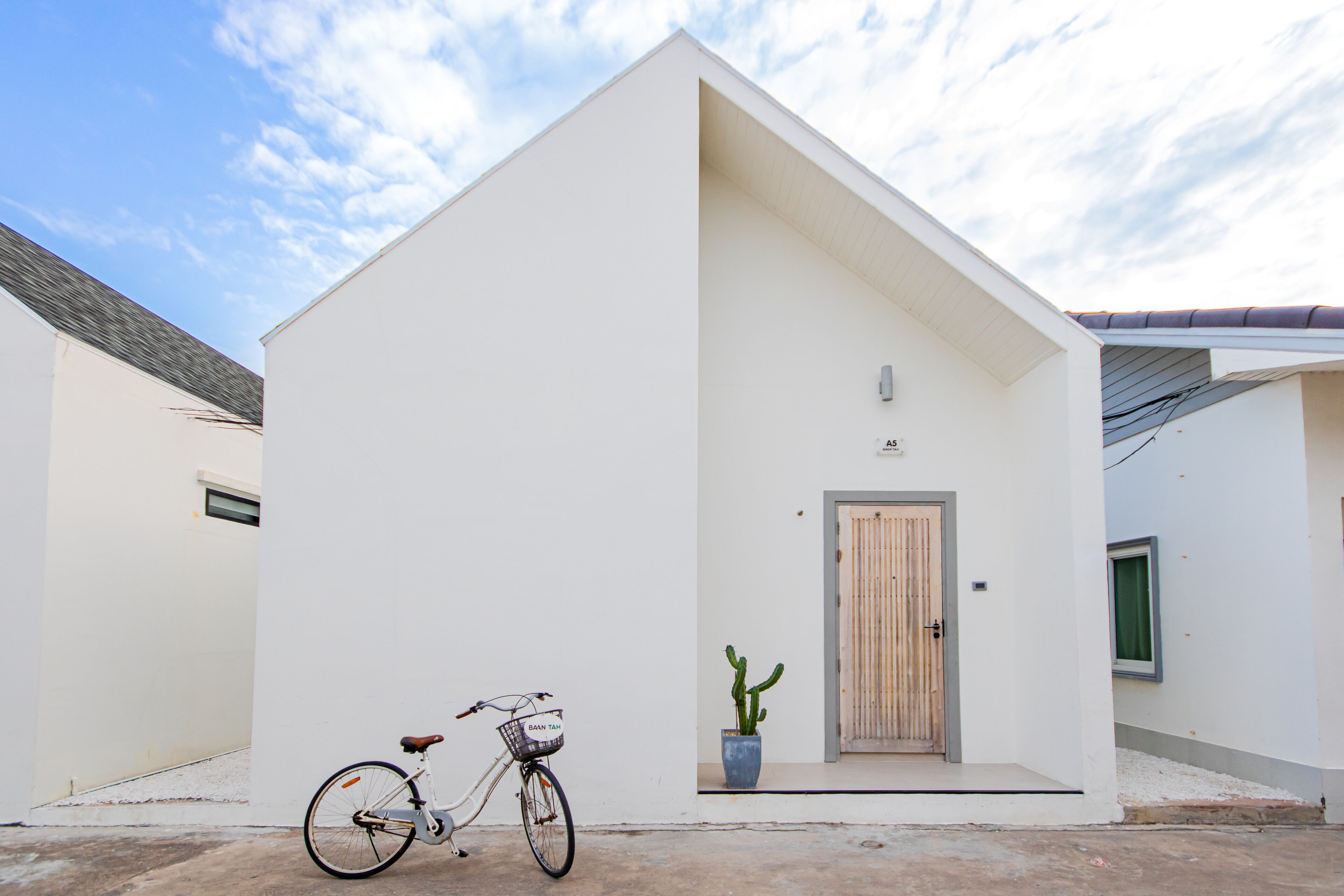 Edifici blanc amb una porta de fusta i una bicicleta aparcada al davant.