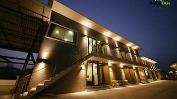 Um edifício moderno de dois andares, com escadaria que leva ao andar superior, janelas amplas e iluminação externa.