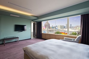A hotel room with a bed, a bench, a TV, and a large window offering a city view. - 52 Hotel (Taichung)