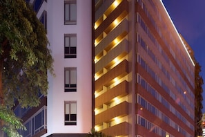 A multi-story hotel with a modern design, featuring a prominent vertical column and a series of balconies with lighting. - 52 Hotel (Taichung)