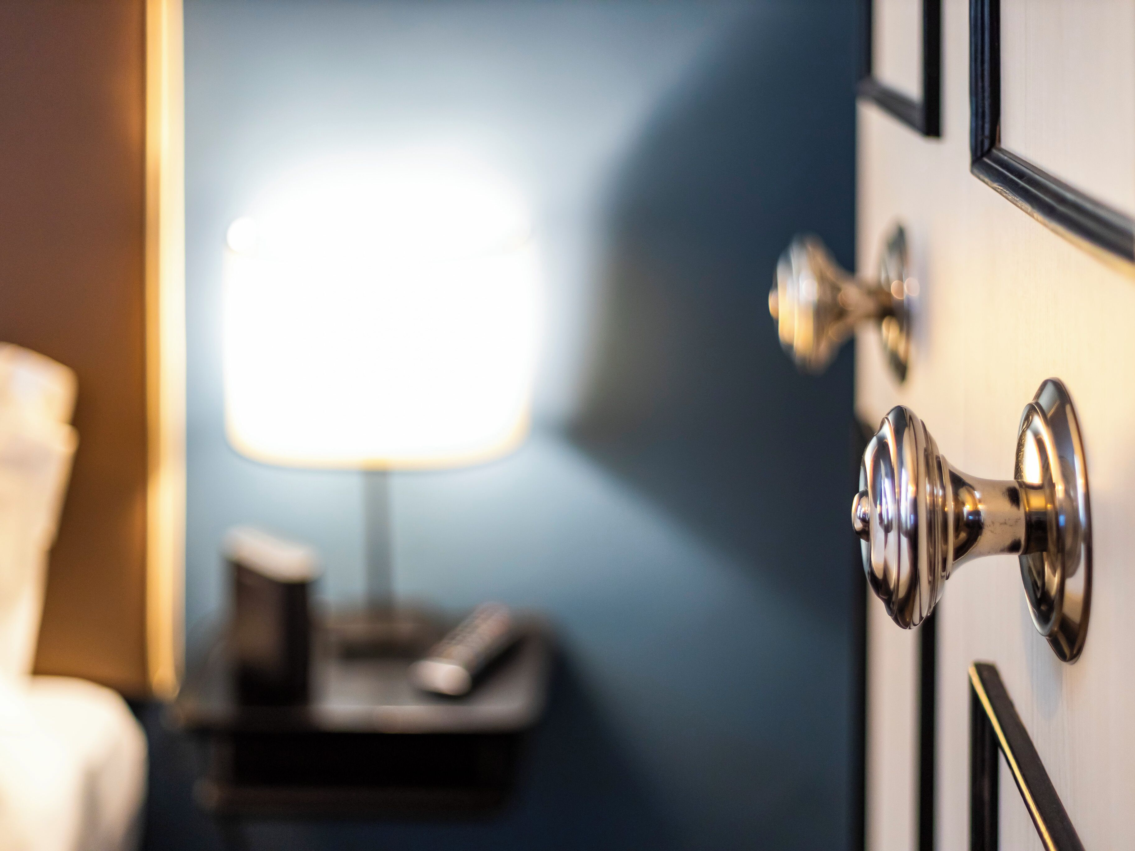 Una habitación de hotel con una puerta, una mesita de noche y una lámpara.