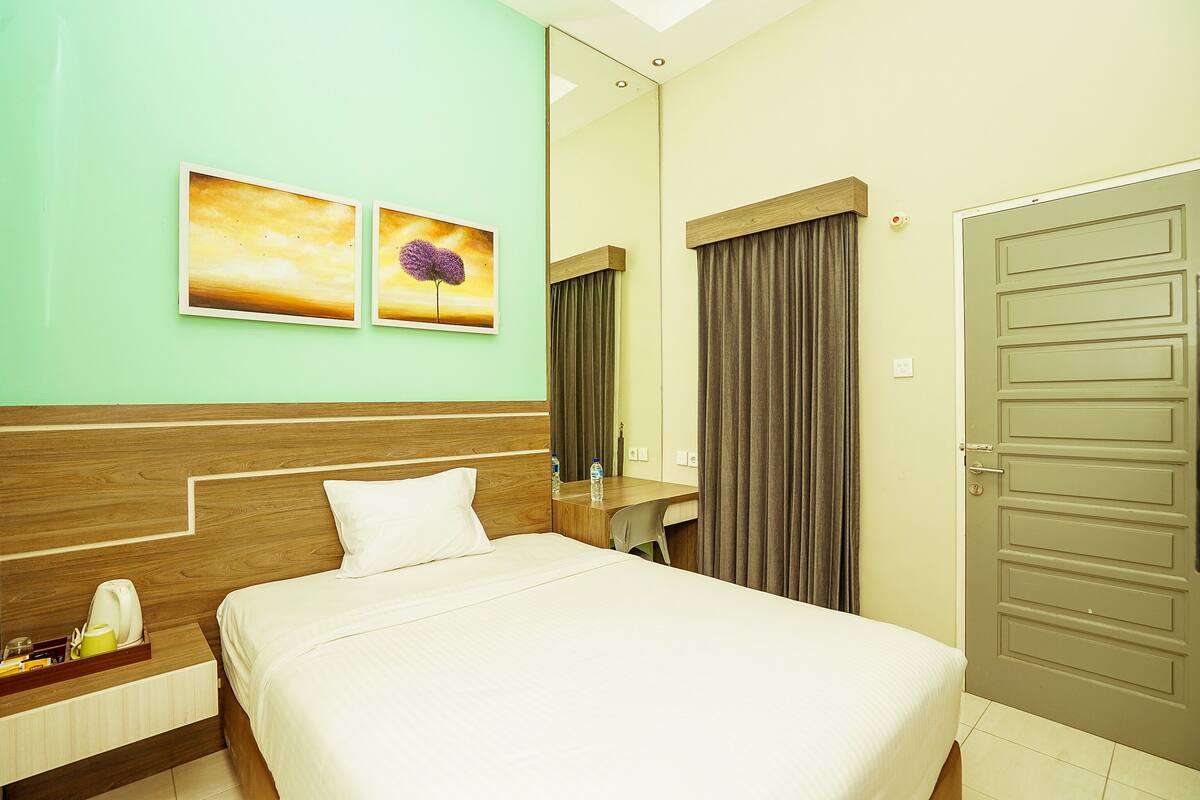 Ein Hotelzimmer mit Bett, Nachttisch, Spiegel und Tür.