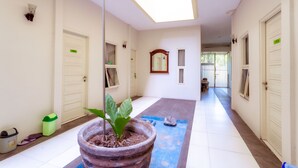 A hallway with white walls, a skylight, and a potted plant. - Ardhya Guesthouse Syariah by Ecommerceloka (Sidoarjo)