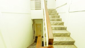 A staircase with a wooden handrail and stone steps leading to a door. - Ardhya Guesthouse Syariah by Ecommerceloka (Sidoarjo)