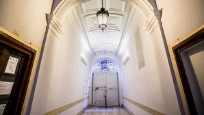 Un couloir avec un plafond blanc, un lustre et une porte au fond.