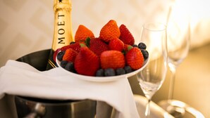 Una botella de champán Moët, un bol de fresas y arándanos, y una copa de vino sobre una mesa.