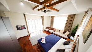 A bedroom with a bed, a sofa, a ceiling fan, and a large window with curtains. - PARADISE Pool Villa Pattaya in Tropicana Village (Pattaya)