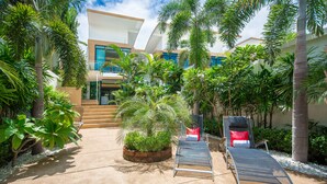 A modern outdoor area with a pool, lounge chairs, and a staircase leading to a building. - PARADISE Pool Villa Pattaya in Tropicana Village (Pattaya)