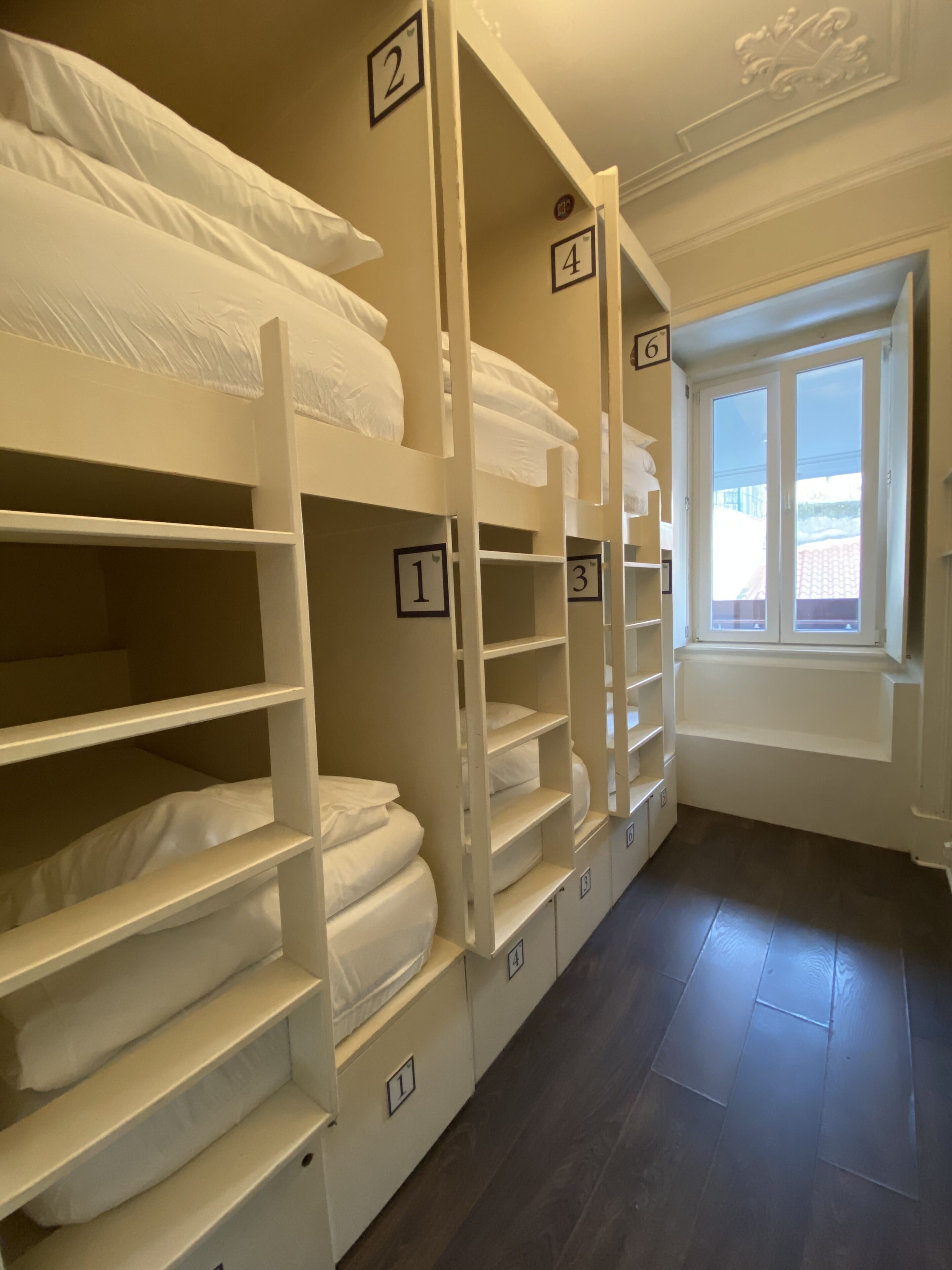 Een kamer met stapelbedden, genummerde opbergvakken en een raam met uitzicht.