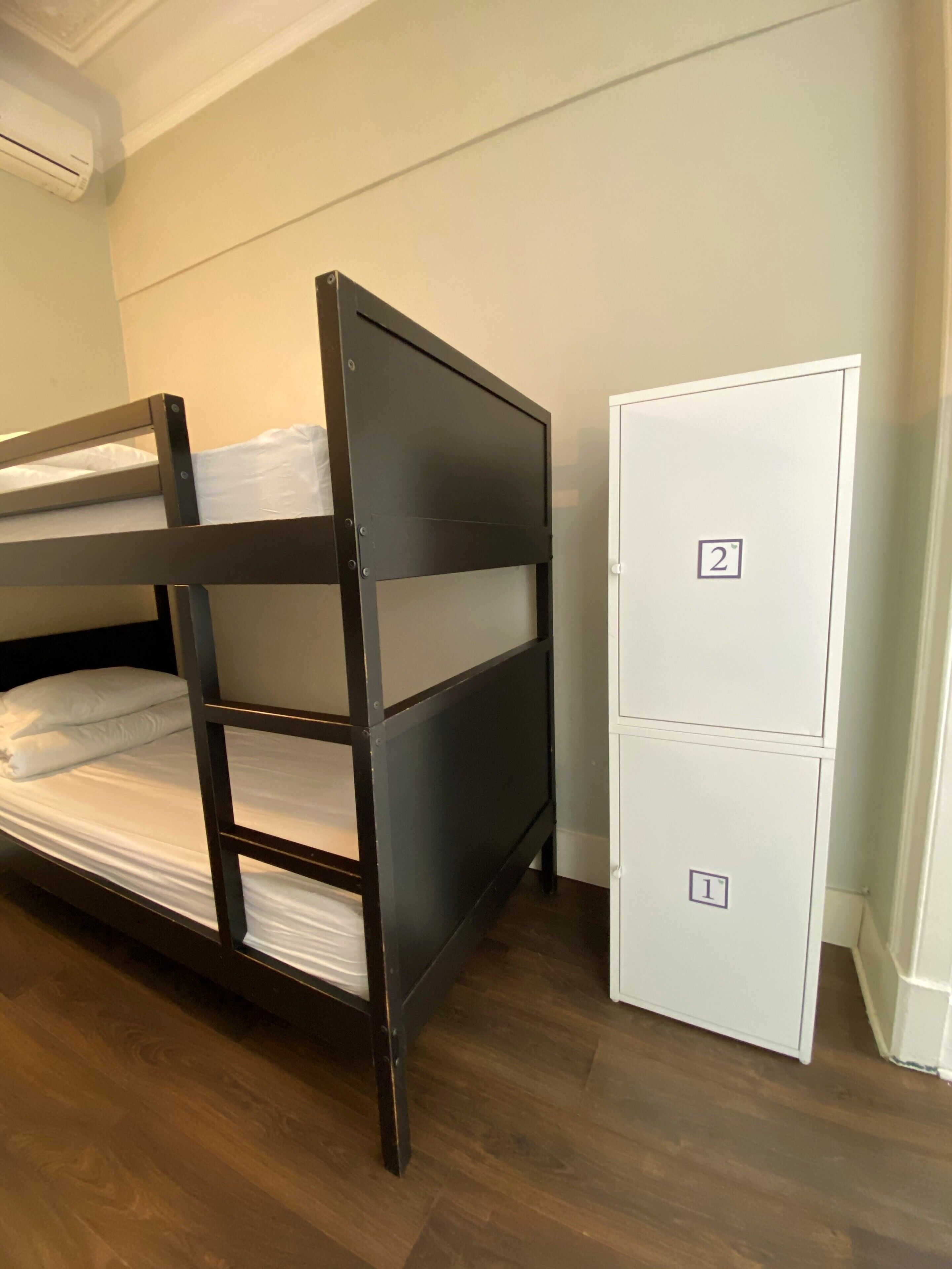 A bunk bed with two levels, a white wardrobe with two compartments, and a wooden floor.
