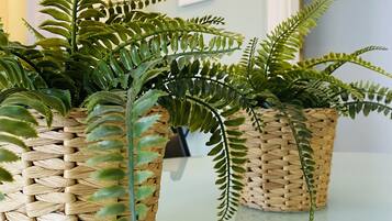 Three woven baskets containing green plants on a reflective surface.