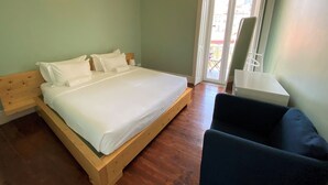 A room with a wooden bed, a small table, and a chair. - Green Heart Hostel (Lisbon)