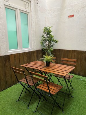 Une table en bois, quatre chaises, une plante en pot et une fenêtre à vitre dépolie.