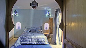 A bedroom with a bed, a hanging lantern, and two wall sconces. - Riad Couleurs du Sud (Marrakech)