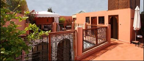 A courtyard with a wrought iron gate, a white umbrella, and a wooden door.