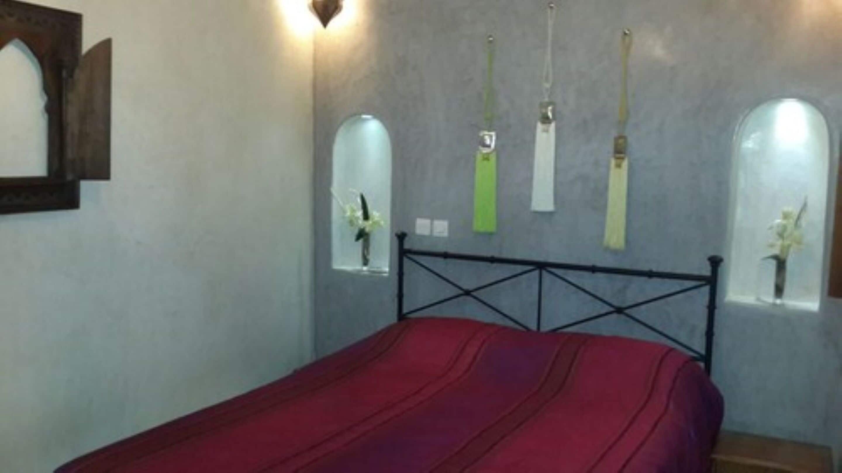 Une chambre à coucher avec un lit, un miroir fixé au mur et un mur orné de trois objets décoratifs.
