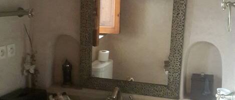 A bathroom with a sink, mirror, and decorative wall sconces.
