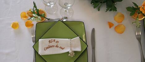 A table set with a green placemat, a folded napkin with text, and a silver fork and knife.
