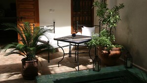A patio with a table and chairs, potted plants, and a lantern. - Riad Couleurs du Sud (Marrakech)