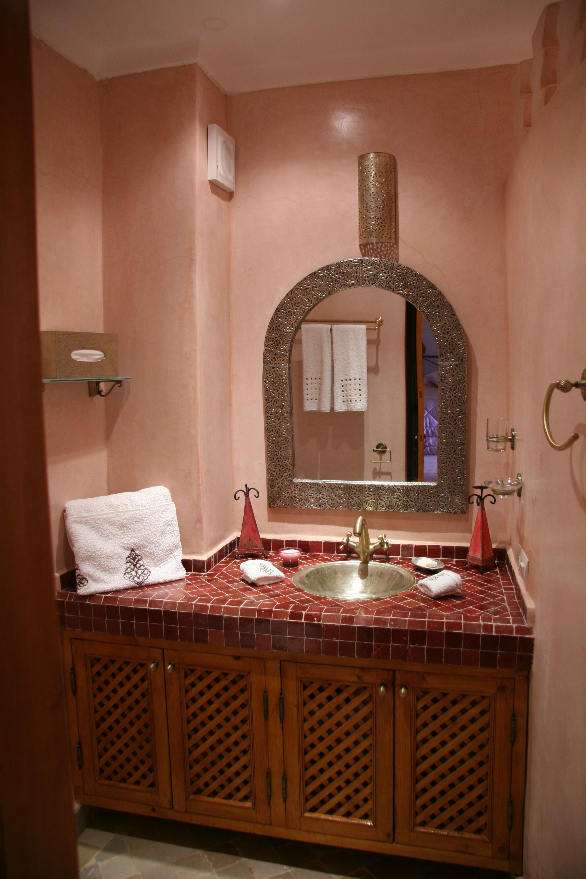 A bathroom with a tiled vanity, a sink, and a mirror.