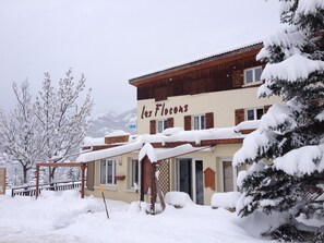 Ein Gebäude mit einem Schild, auf dem "les Flocons" steht, vor einer verschneiten Landschaft.