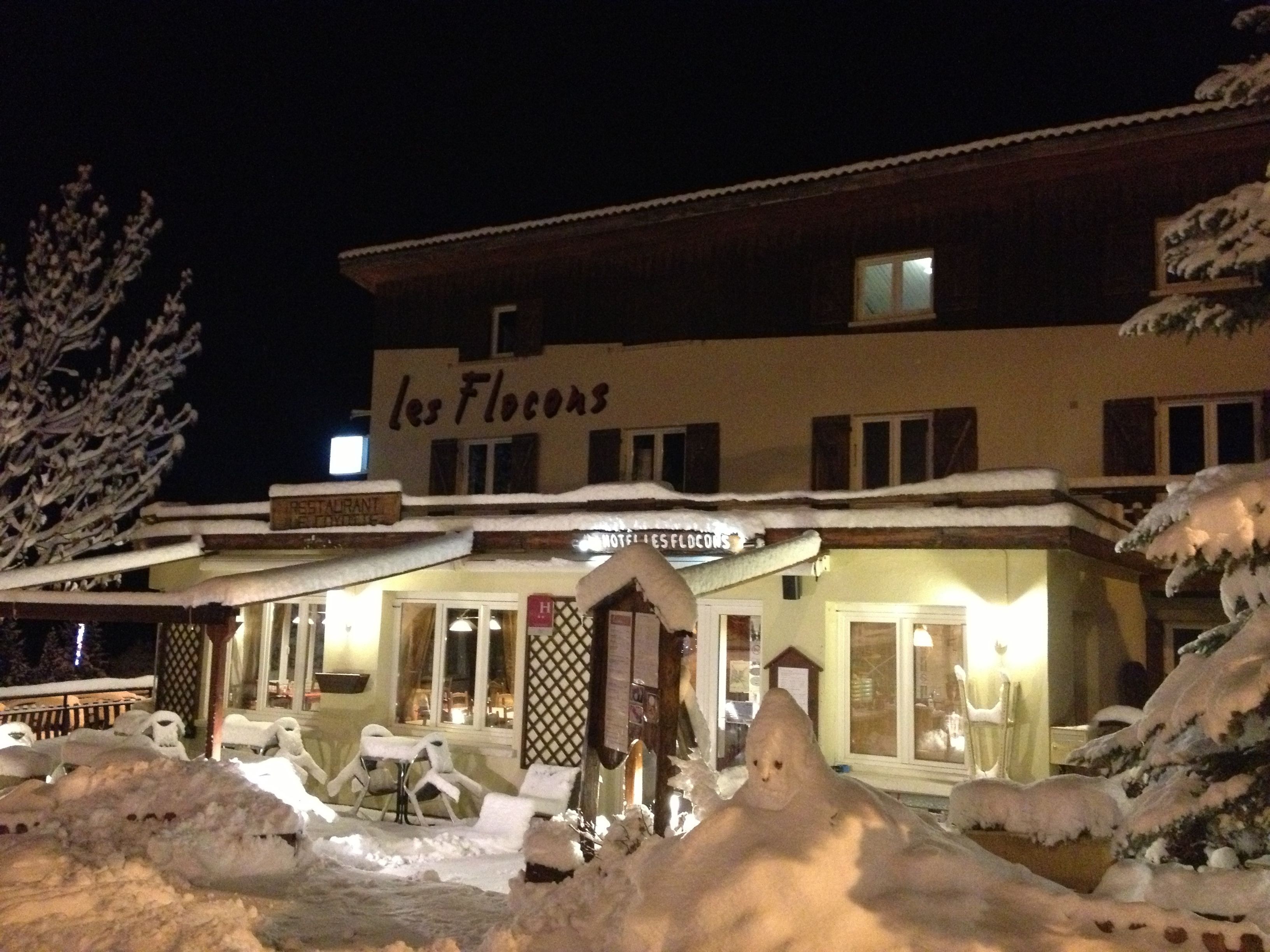 Un hôtel appelé « Les Flocons », doté d’une terrasse et situé dans un environnement enneigé.