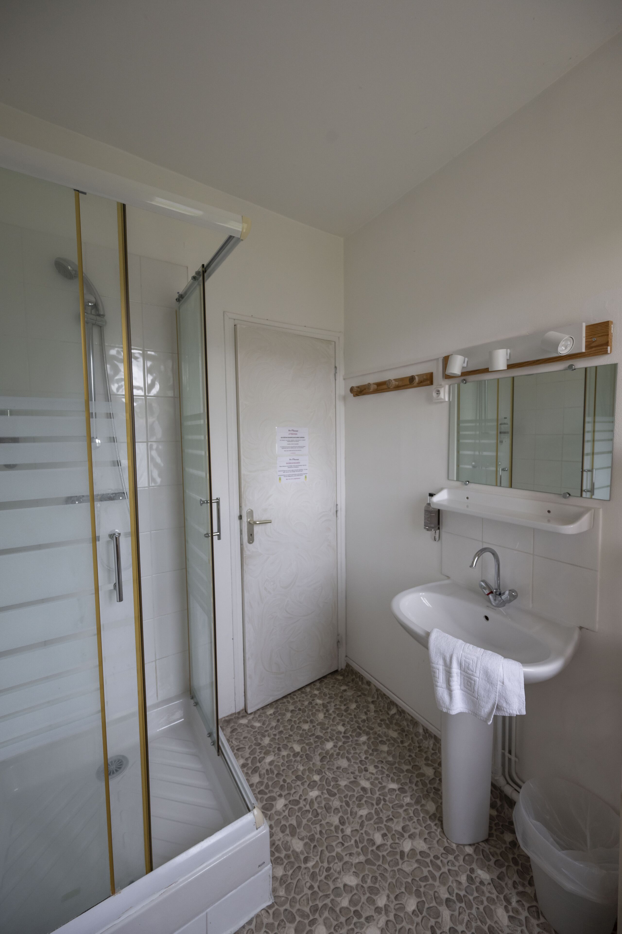 A bathroom with a glass shower enclosure, a sink, and a toilet.