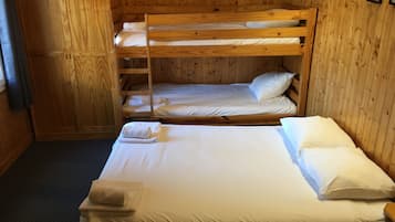A bunk bed room with wooden walls and a single bed at the bottom.