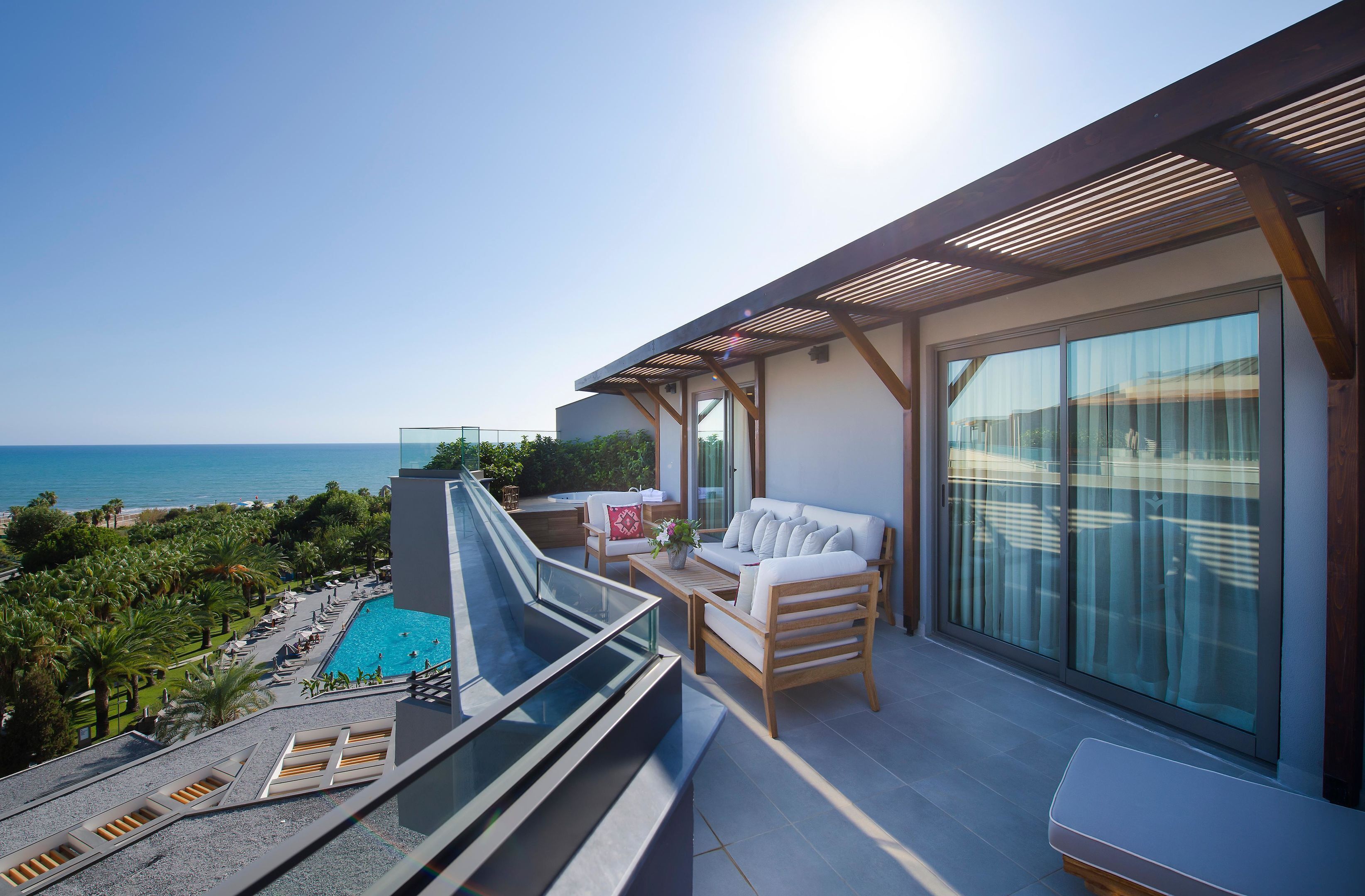 Un balcón con piscina, zona de estar y vista al océano.