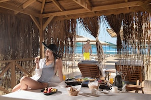 A beachside dining setup with a table, wicker baskets, and a pitcher of juice. - Miramare Beach Hotel (Manavgat)