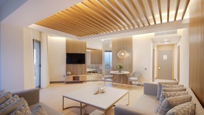 A modern living room with a large sofa, a coffee table, and a dining area with a small table and chairs. - Miramare Beach Hotel (Manavgat)