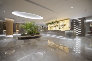 A modern lobby with a marble floor, a reception desk, and a seating area with plants. - Miramare Beach Hotel (Manavgat)