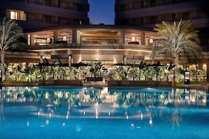 Un hotel con piscina, varios balcones y zonas de estar al aire libre.