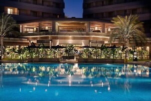 Una piscina techada, una piscina al aire libre, sombrillas