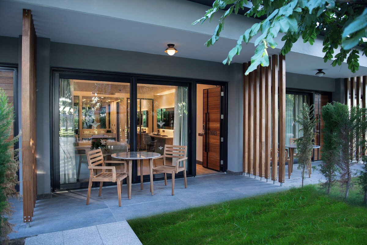 An outdoor dining area with a table and chairs, a glass door entrance, and a modern building facade.
