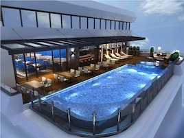 A modern hotel with a rooftop infinity pool, outdoor seating, and a bar area.